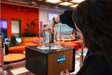 Person using a futuristic coffee machine in a modern cafe setting